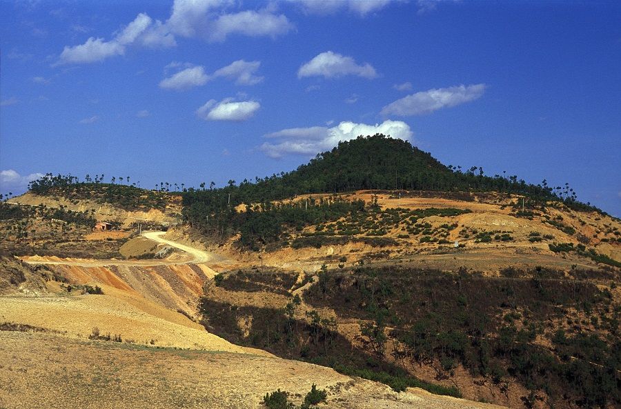 Landscape of light-coloured rock and wooded hill