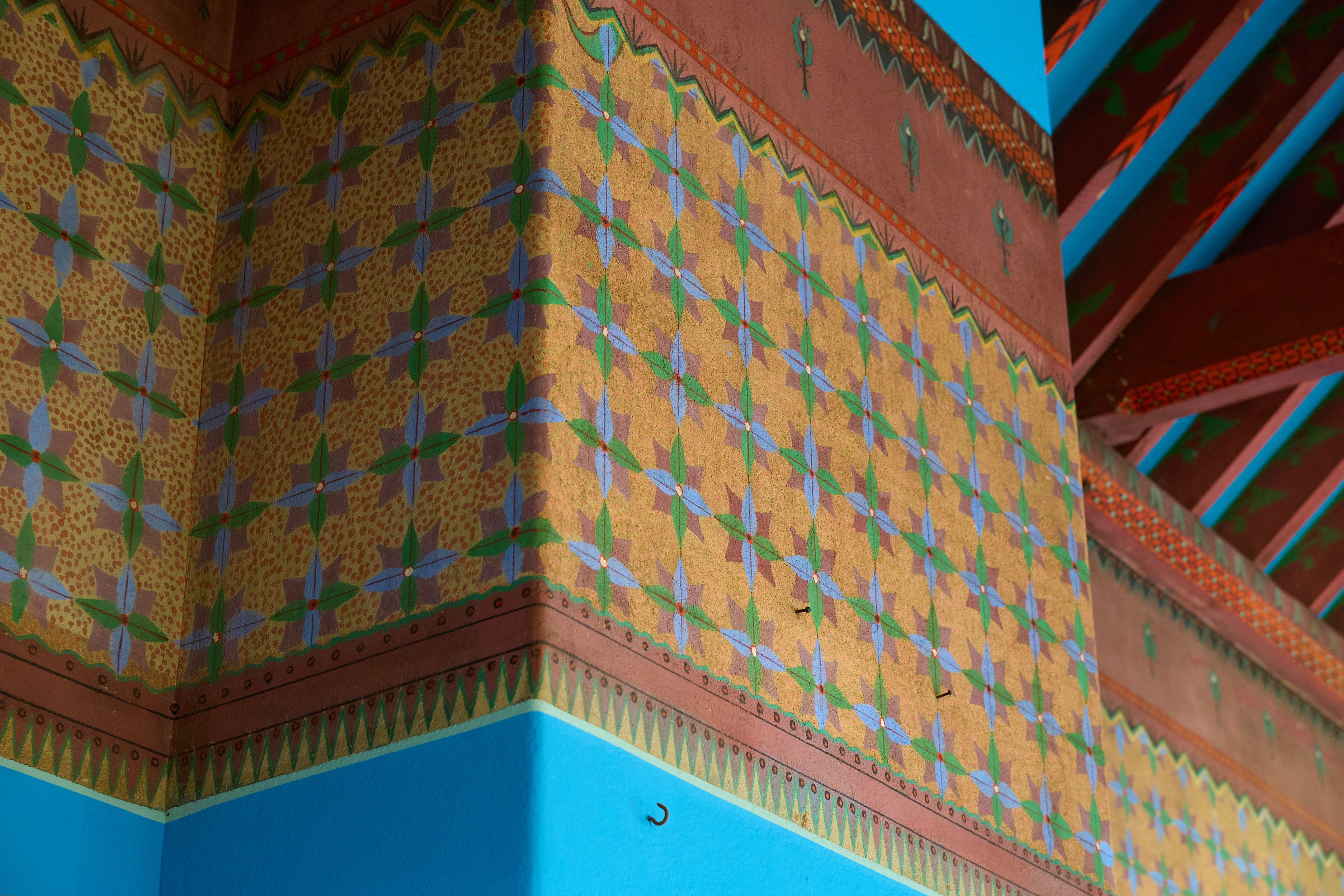Repeating painted decoration at top of blue walls